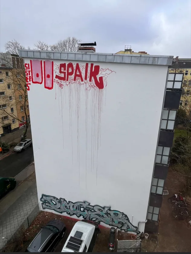 Graffiti in großer Höhe an einer weißen Giebelwand in Berlin