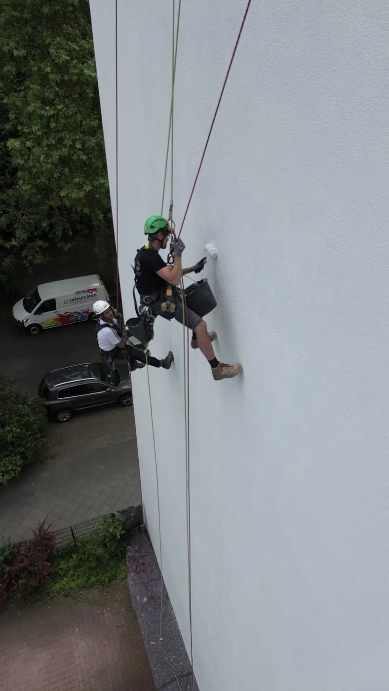Seilkletterer bei der Graffitibeseitigung an einer hohen Fassade in Berlin