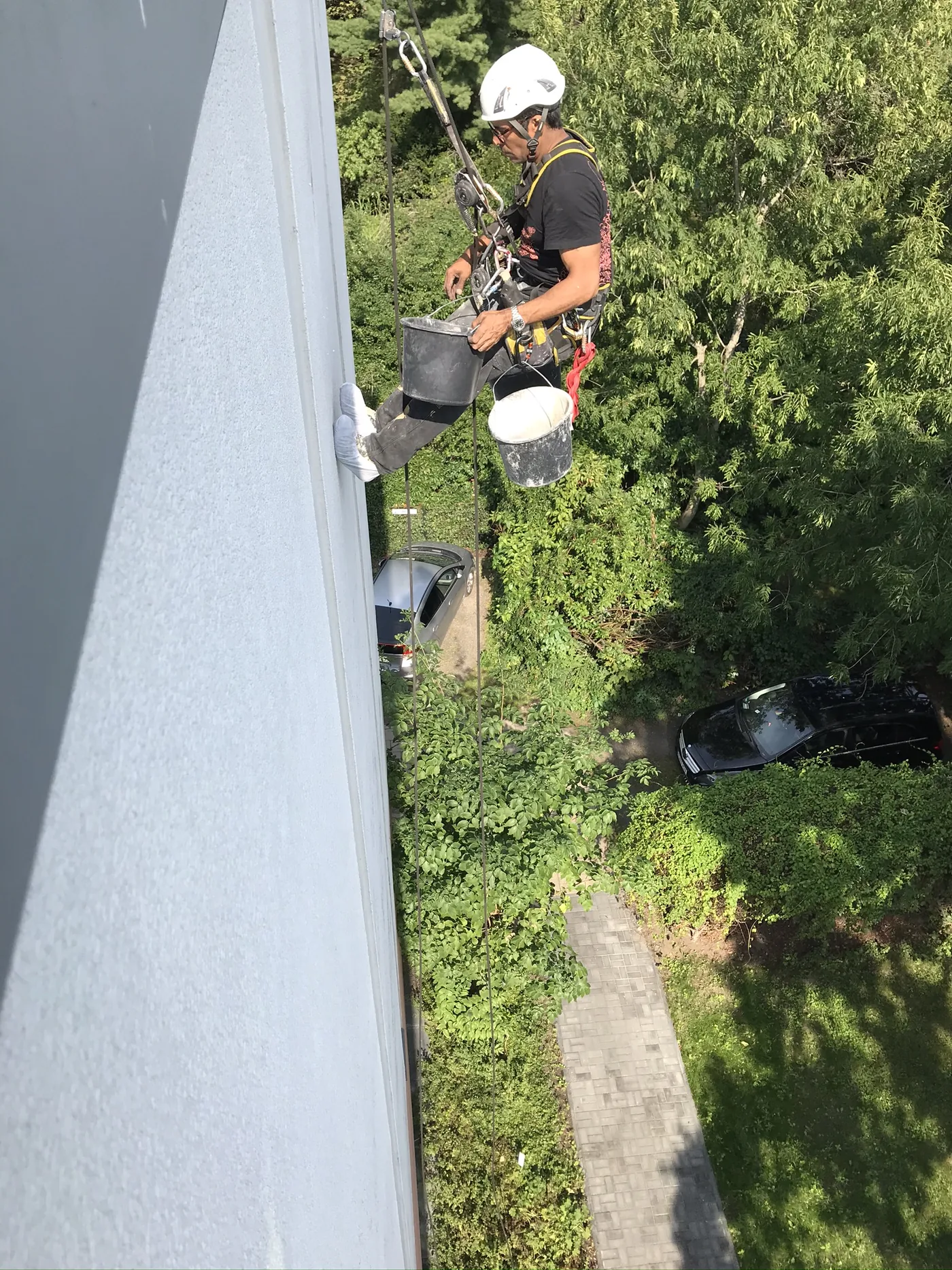 Blick von oben auf einen Seilkletterer bei der Fassadenreparatur